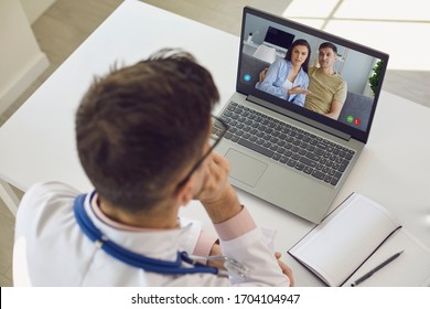 Doctor Medical Online Call.Shoulder View Doctor Therapist Psychologist Speaks With Couple Video Chat Using A Laptop In A Clinic Office.
