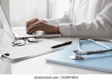 Doctor medical professional working on laptop, focus on stethoscope. Physician, therapist or practitioner filling medical documents, writing prescription for patient. Health care, medicine concept