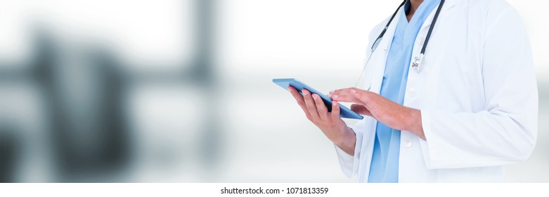 Doctor Mid Section Holding Tablet Against Blurry Grey Office