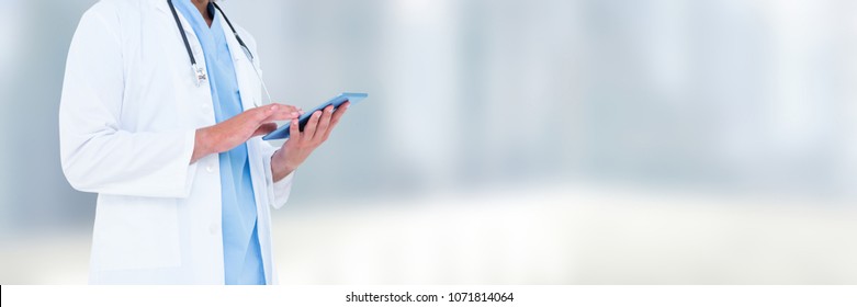 Doctor Mid Section Holding Tablet Against Blurry White Room