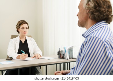 Doctor And Middle Aged Male Patient During Consultation In Office