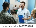 Doctor and military man shaking hands while standing in a lobby at the hospital. 