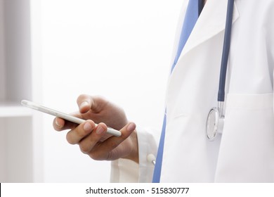 Doctor With Mobile Phone In Hands In Office