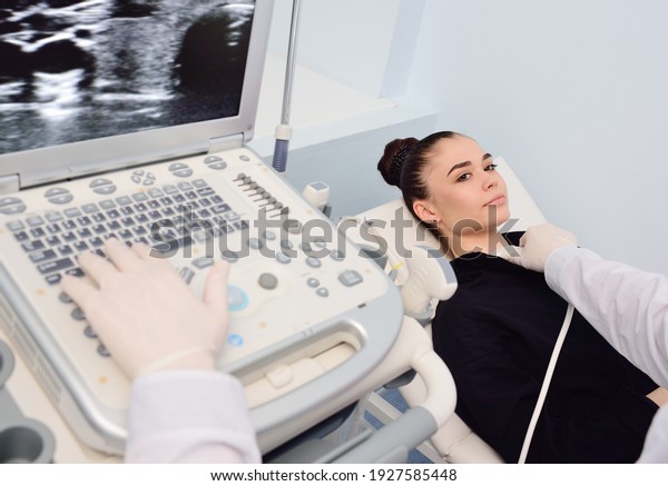a doctor in a modern\
diagnostic clinic examines the thyroid gland of a patient of a\
young attractive woman on an ultrasound machine. Prevention of\
thyroid cancer.