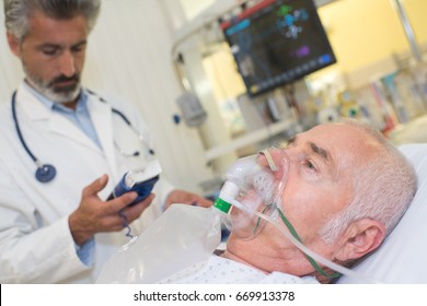 Doctor Near Patient Wearing Oxygen Mask In Hospital Room