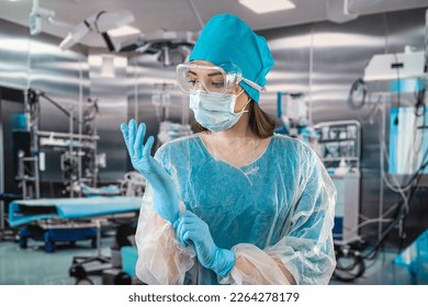 doctor or nurse in a blue coat puts on blue rubber gloves prepares to examine a patient in the operating room. medicine. operating room doctors and surgeons. - Powered by Shutterstock