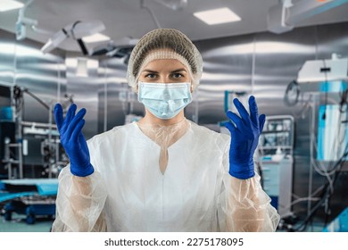 doctor or nurse in a blue coat puts on blue rubber gloves prepares to examine a patient in the operating room. medicine. operating room doctors and surgeons. - Powered by Shutterstock