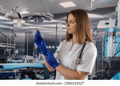 doctor or nurse in a blue coat puts on blue rubber gloves prepares to examine a patient in the operating room. medicine. operating room doctors and surgeons. - Powered by Shutterstock