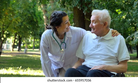 Doctor, Nurse, Care For The Elderly, Girl (woman) And Grandfather Sitting In A Wheelchair, Walking In The Park. Concept: A Boarding House, A Sanatorium, A House For The Elderly, Help For The Elderly.