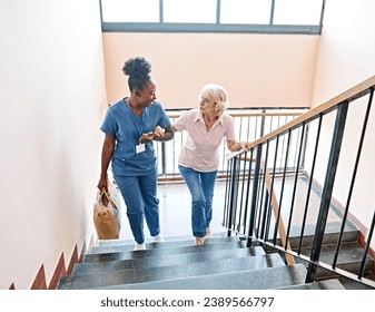 Doctor or nurse caregiver helping disabled senior woman walking down the stairs at home or nursing home - Powered by Shutterstock