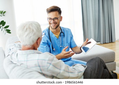 Doctor Or Nurse Caregiver Helping Senior Man With A Tablet At Home Or Nursing Home