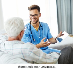 Doctor Or Nurse Caregiver Helping Senior Man With A Tablet At Home Or Nursing Home