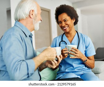 Doctor Or Nurse Caregiver With Senior Man Drinking Tea Or Coffee At Home Or Nursing Home