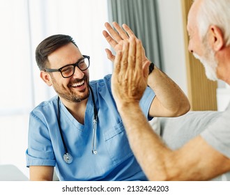 Doctor or nurse caregiver with senior man giving high five at home or nursing home - Shutterstock ID 2132424203
