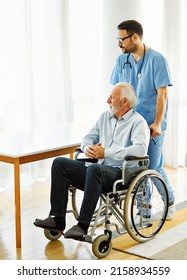 Doctor Or Nurse Caregiver With Senior Man In A Wheelchair  Holding  A Document Paperwork At Home Or Nursing Home