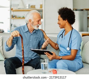 Doctor Or Nurse Caregiver With Senior Man Holding Walking Cane At Home Or Nursing Home