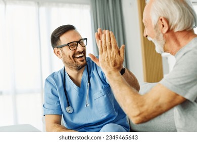 Doctor or nurse caregiver with senior man giving high five at home or nursing home