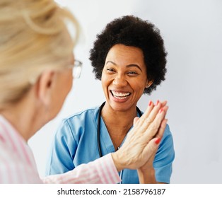 Doctor Or Nurse Caregiver With Senior Woman Giving High Five At Home Or Nursing Home