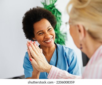 Doctor Or Nurse Caregiver With Senior Woman Giving High Five At Home Or Nursing Home
