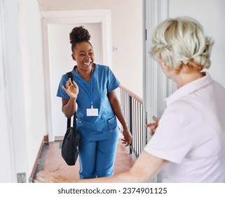 Doctor or nurse caregiver with senior woman at home or nursing home, a caregiver standing on the front door arriving and being welcomed by a senior woman - Powered by Shutterstock