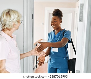 Doctor or nurse caregiver with senior woman at home or nursing home, a caregiver standing on the front door arriving and being welcomed by a senior woman - Powered by Shutterstock