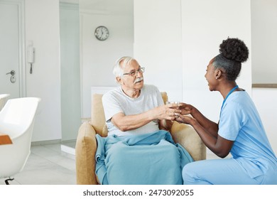 Doctor or nurse caregiver serving a glass of waterl to senior man at home or nursing home - Powered by Shutterstock