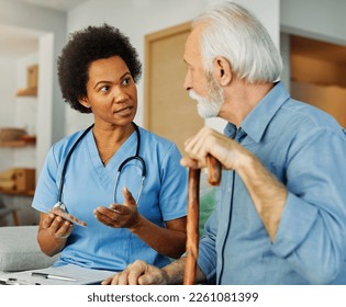 Doctor or nurse caregiver showing a prescrption drug to senior man at home or nursing home - Powered by Shutterstock