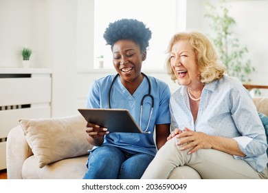 Betreuer des Arztes oder der Krankenschwester, der älteren Frauen einen Tablettenbildschirm zeigt und zu Hause oder zu Hause lacht