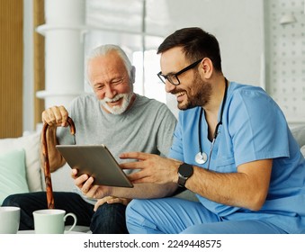 Doctor or nurse caregiver showing a tablet screen to  senior man and laughing at home or nursing home - Powered by Shutterstock