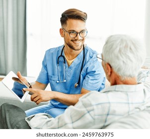 Doctor or nurse caregiver showing a tablet screen to  senior man at home or nursing home - Powered by Shutterstock