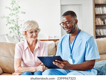 Doctor or nurse caregiver talking to senior woman at home or nursing home - Powered by Shutterstock