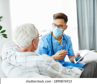 Doctor or nurse caregiver wearing a protective mask helping senior man with a tablet at home or nursing home