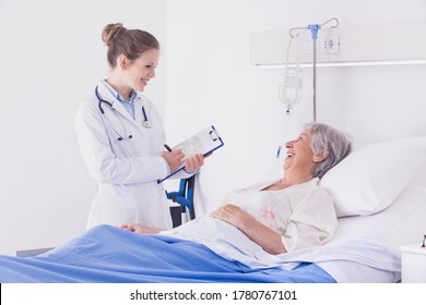 Doctor or nurse chatting to a senior woman patient during ward rounds at a hospital taking notes as they smile at each other - Powered by Shutterstock