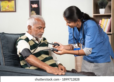 Doctor Or Nurse Checking Blood Pressure Or BP Of Patient At Home - Concept Of Elderly People Routine Home Health Care Or Service