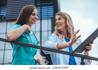 Doctor and nurse discussing over a medical report in hospital. Female  doctor and nurse checking clinical report of patient online. Healthcare staff having discussion outdoors of private clinic. - Powered by Shutterstock