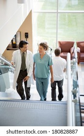 Doctor And Nurse Discussing While Walking On Stairs In Hospital