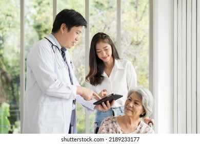 Doctor, Nurse And Elderly Patient Woman Sit On Wheelchair. Male Doctor Visit Elderly Asian Woman On Wheelchair At The Hospital