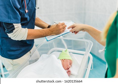 Doctor and nurse examining newborn baby in hospital.