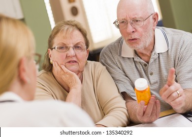 Doctor Or Nurse Explaining Prescription Medicine To Attentive Senior Couple.