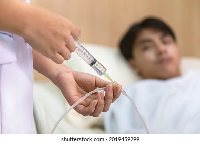Doctor Or Nurse Giving Medicine Injection To Iv Tube For Patient Treatment At Hospital. Healthcare And Medical Concept.