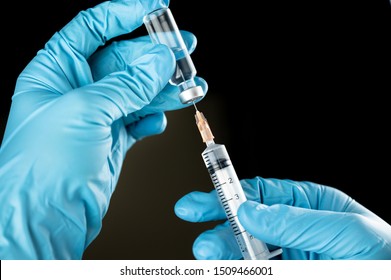 Doctor Or Nurse Hand In Blue Gloves Holding Flu, Measles Vaccine Shot For Baby And Adult Vaccination On Black Background, Medicine And Drug Concept