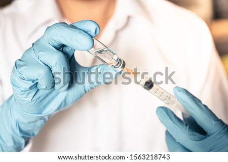 Doctor or nurse hand in blue gloves holding flu, measles vaccine injection with syringe prepare for baby vaccination, medicine and drug concept.