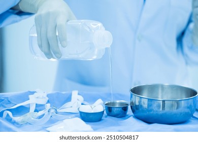 Doctor or nurse hand with surgical set and medical equipment on blue surgical tray inside operating room.Sterile surgical instrument tool equipment for surgery.Infection control. - Powered by Shutterstock