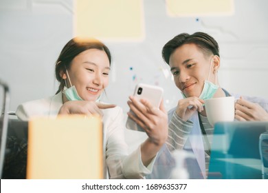 Doctor And Nurse Having Conversation During Break Lunch Time Lookign At Smartphone Inside Hospital Room.