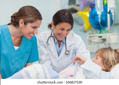 Doctor And Nurse Looking At A Child In Hospital Ward