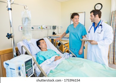 Doctor and nurse looking at each other while patient lying on bed in hospital - Powered by Shutterstock