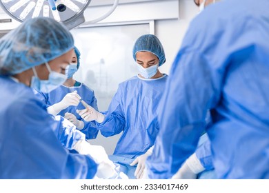 Doctor and nurse medical team are performing surgical operation at emergency room in hospital. assistant hands out scissor and instruments to surgeons during operation. - Powered by Shutterstock