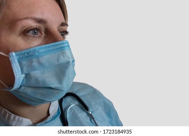 Doctor Or Nurse In Medical Uniform Mask And Stethoscope. Close-up Portrait Of White Woman Not Looking Into The Camera In Half Face Position On Gray Isolated Background With Copy Space