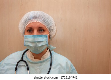 Doctor Or Nurse In Medical Uniform Mask Cap And With Stethoscope. Portrait Of White Woman Not Looking Into The Camera In Front Position On Light Textured Background With Copy Space