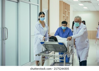 Doctor, Nurse And Paramedics Carrying Patient On Gurney Pushing And Running Towards The Operating Room At The Hospital. Professional Staff Team Saving Lives. Healthcare Insurance Concept